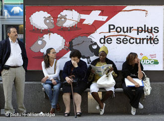 people wait for a bus in front of the controversial SVP poster deemed racist in last year's polls people wait for a bus in front of the controversial SVP poster deemed racist in last year's polls