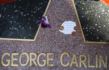 a note and a flower are seen on the star of comedian George Carlin on the Walk of Fame in Hollywood