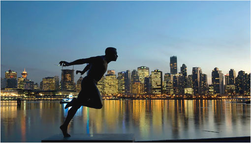 A statue of runner Harry Jerome stands against the Vancouver skyline