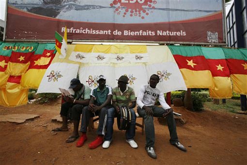 Cameroonian salesmen wait for customers in front of a display of Cameroonian flags and locally-made Vatican City flags, which they commissioned for Pope Benedict XVI's visit, in central Yaounde, Cameroon Monday, March 16, 2009. Pope Benedict XVI will arrive in Cameroon Tuesday on his first trip to Africa, the fastest-growing region for the Roman Catholic church