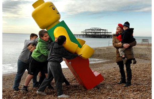 children play with a giant Lego man which has washed up on a beach in Brighton after floating all the way from Holland in 2008