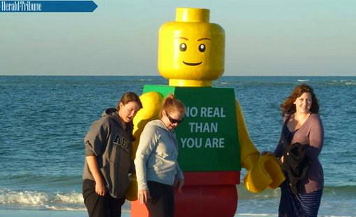 Florida, US, 2011 - beachgoers pose with giant Lego man on Siesta Key Public Beach before it was picked up by the Sarasota County Sheriff's Office