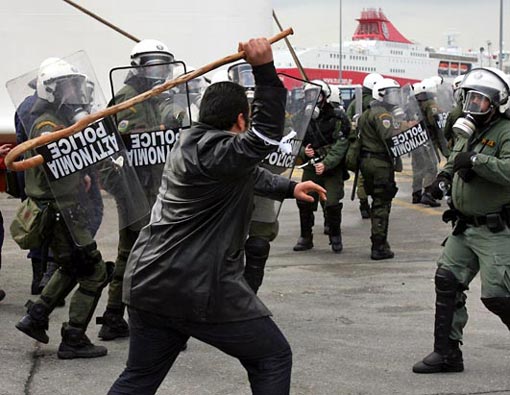 after nearly two weeks of demonstrations, Greek farmers used their tractors to block border crossings and highways across the country for days, demanding financial help from the government. A farmer hits a riot police officer with his crook at the main port of Piraeus, near Athens, Feb. 2, 2009