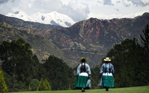 Two Aymara indigenous women walk through La Paz Golf Club, as the snowy summit of Illimani appears in the background on November 26, 2008. La Paz Golf Club is considered to be the highest in the world, around 11,000 feet above sea level. Founded in 1912, the Club sits in the upscale district of southern La Paz, and its exclusive facilities receive the local elite
