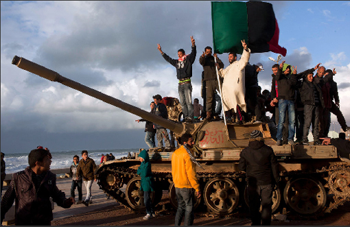 Eastern Libyans celebrate atop a surrendered military tank in the town square of Benghazi on Thursday