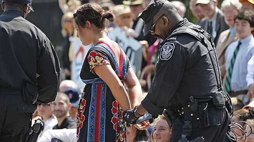 US Park Police officer handcuffs and arrests a protestor over a proposed pipeline to bring tar sands oil to the US from Canada