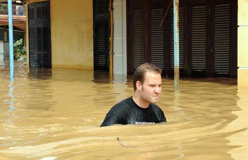 a foreign tourist wades on a flooded street in the town of Hoi An